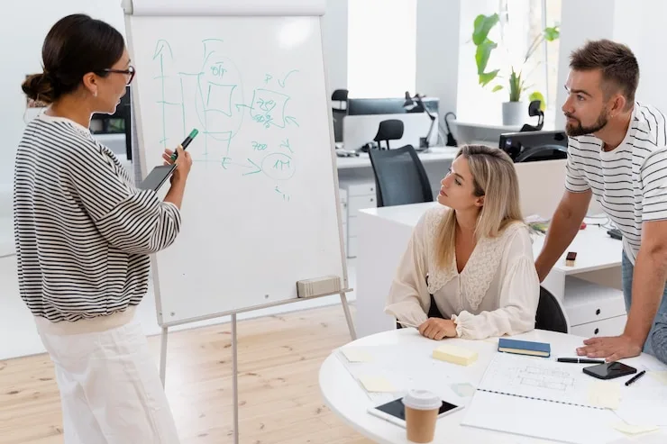 Colleague sketching on a flip chart while two others look on