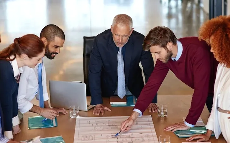 Colleagues leaning over a large printed plan spread across a table