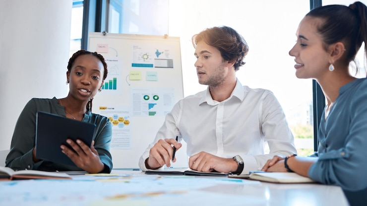Three colleagues comparing notes and diagrams across a table