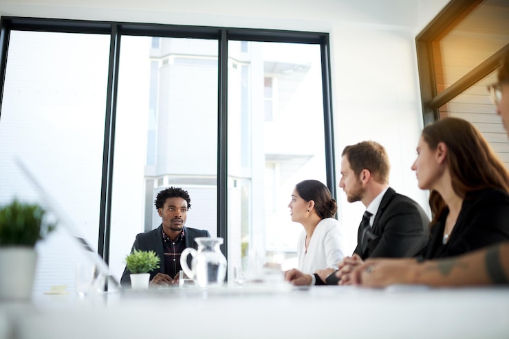 Colleagues in a bright meeting room seated around a table in discussion